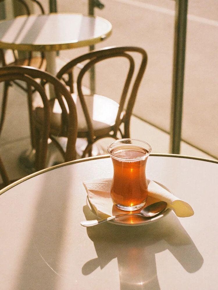 A tulip glass of Turkish tea on a small table by the window